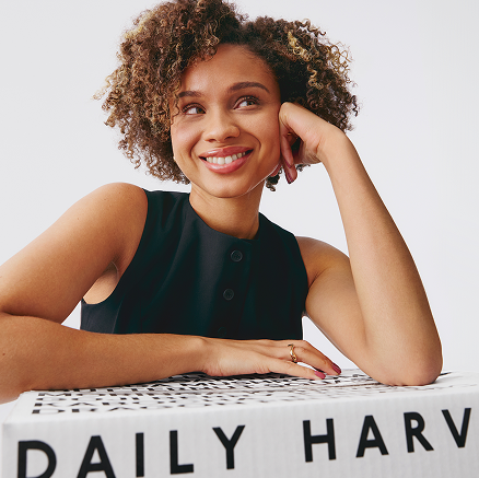 woman smiling on a daily harvest box.