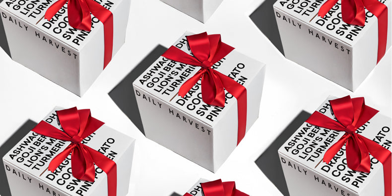 Multiple neatly wrapped white gift boxes with black text and red ribbons on a white surface