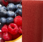 Close-up of a red textured fabric next to fresh blueberries and raspberries on a white surface