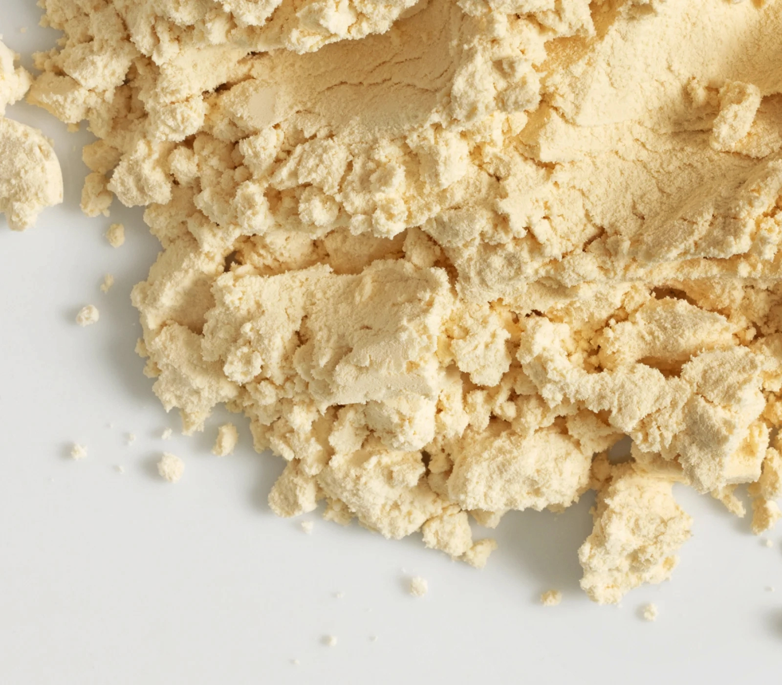 Close-up of a pile of finely ground beige powder on a white surface for product display purposes