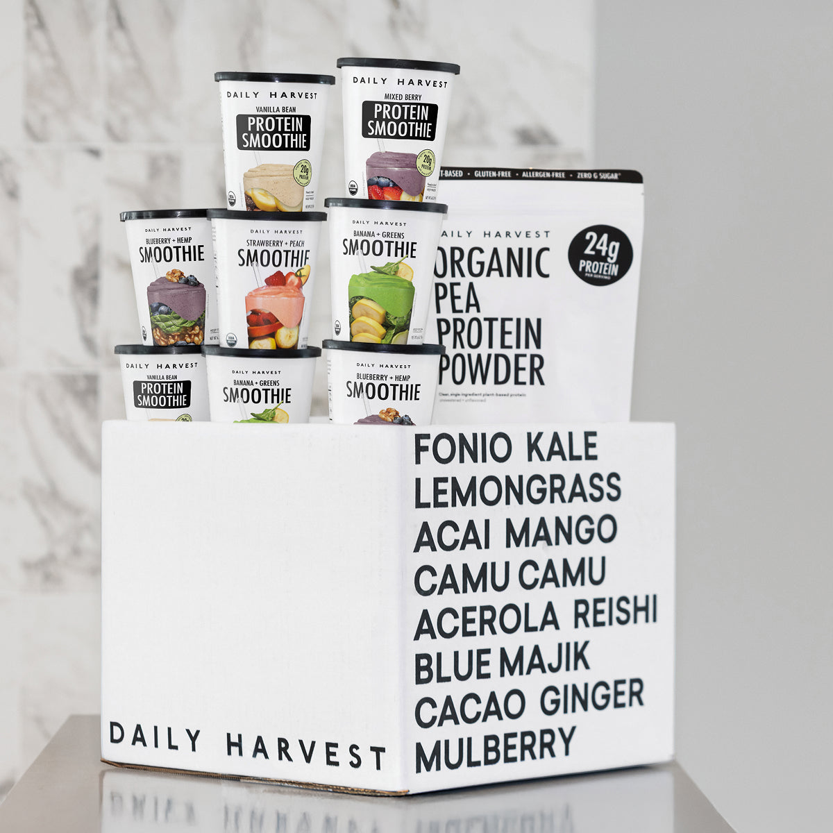 Stack of Daily Harvest protein smoothie cups and organic pea protein powder in branded box on table