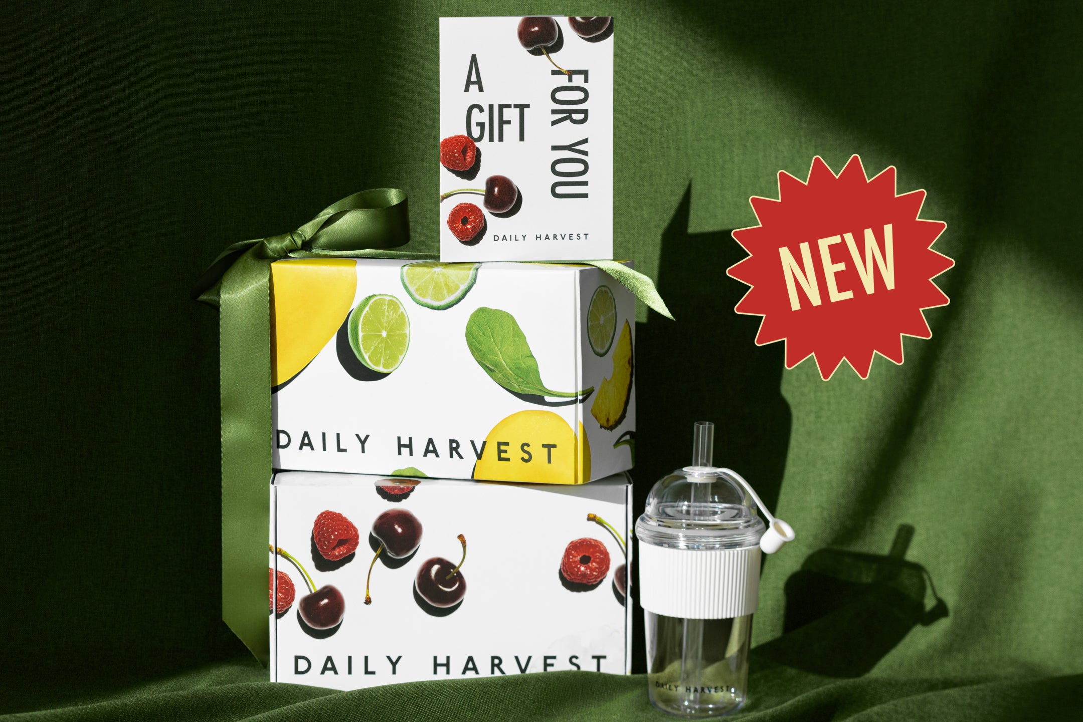 Three Daily Harvest smoothie packages on a green fabric background