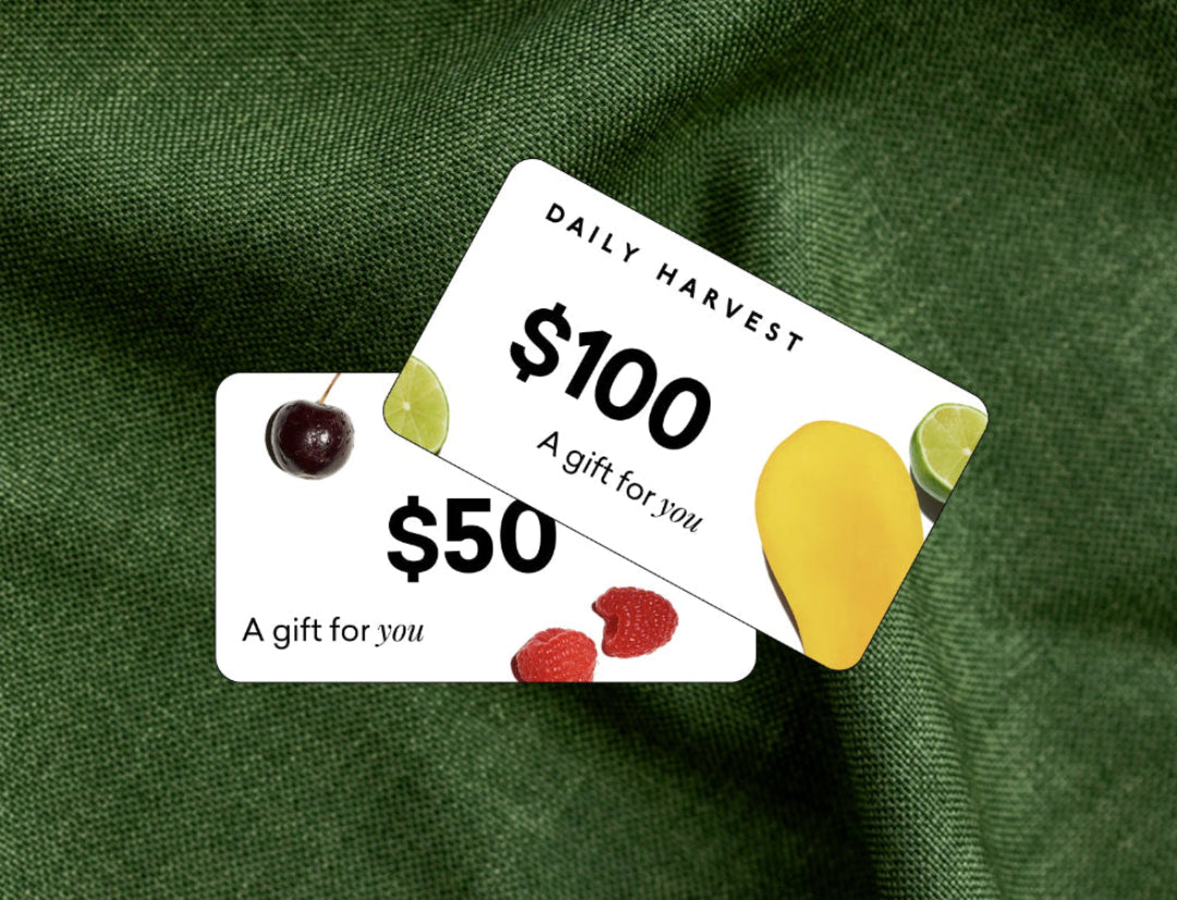 Two gift cards for Daily Harvest on a green fabric background