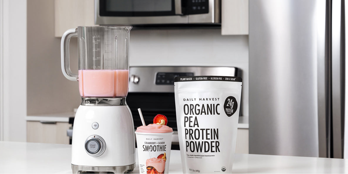 Daily Harvest Harvest Bowl package with prepared meal and Protein Smoothie cup on white table background