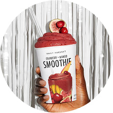 Hand holding a container of Daily Harvest smoothie with a wooden spoon
