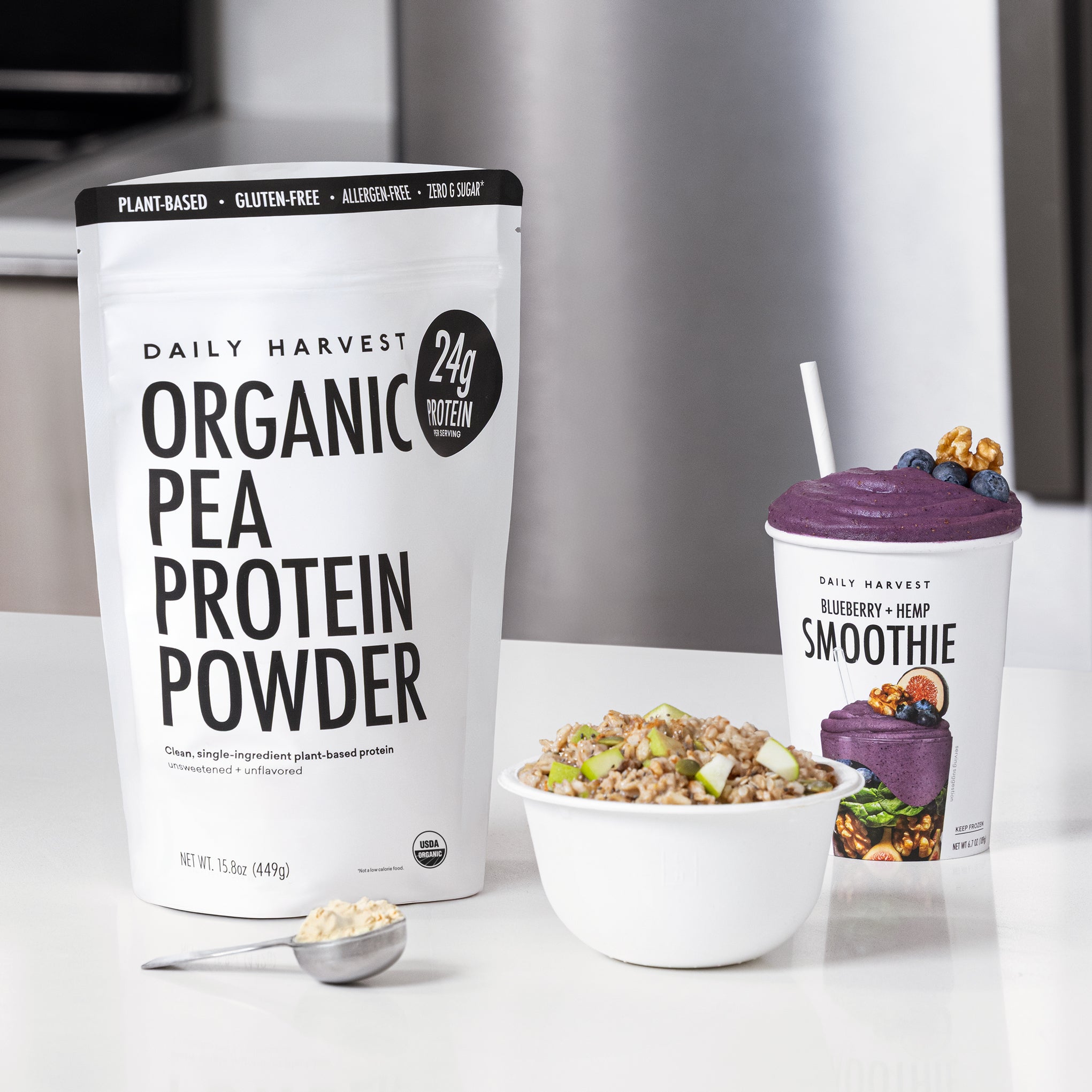 Organic pea protein powder package with a bowl of granola and a blueberry hemp smoothie on a white surface