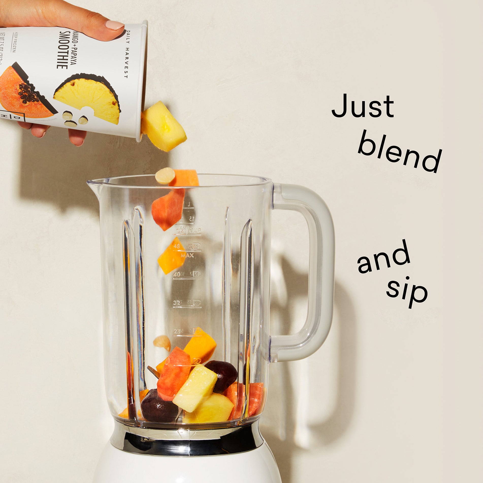 Blender with fruits and a smoothie box, text 'Just blend and sip' on a light background