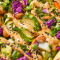 Close-up of a fresh, colorful mixed salad with greens, tomatoes, cucumbers, and sliced vegetables on a white plate