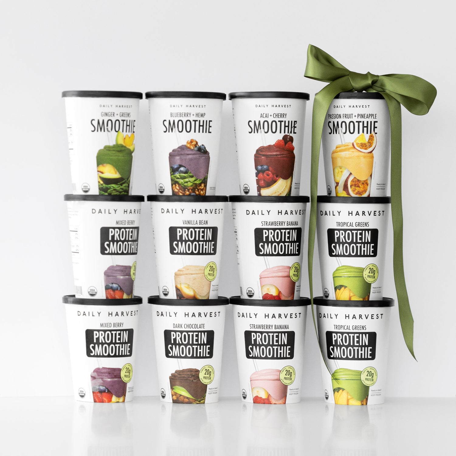 Stacked Daily Harvest smoothie cups tied with green ribbon and black sale tag on white background