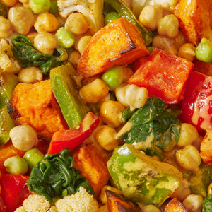 Close up ingredient shot including peppers, sweet potato, chickpeas and spinach.